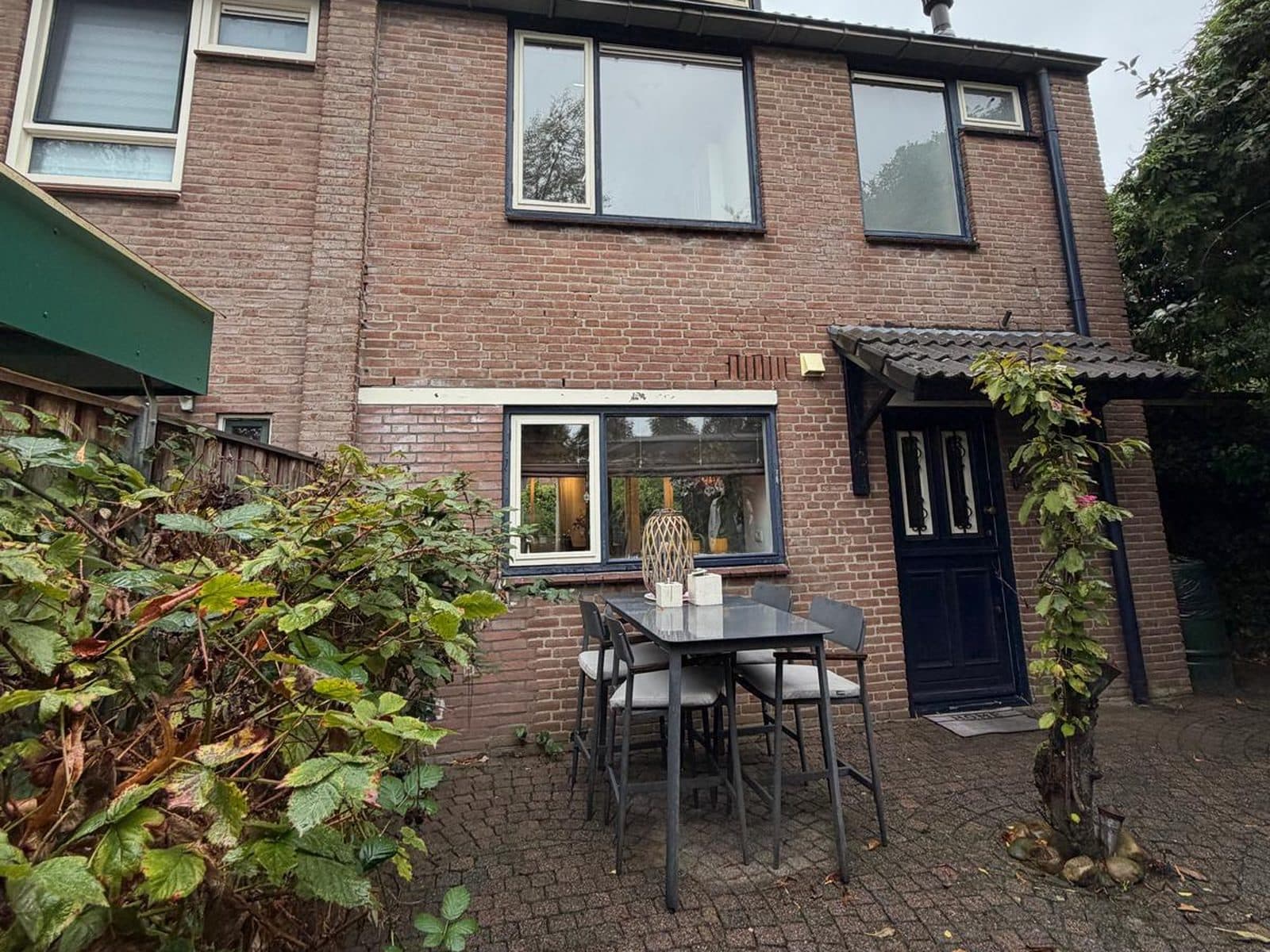 Achtergevel van een bakstenen hoekwoning met terras in Apeldoorn