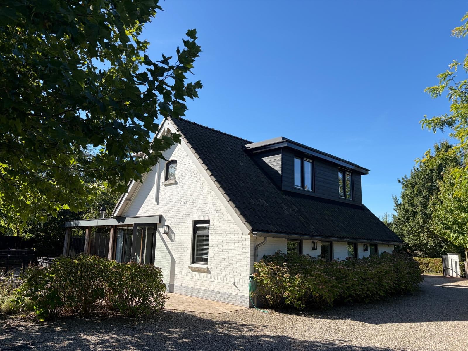 Witte vrijstaande woning met donker pannendak en dakkapel in Loo